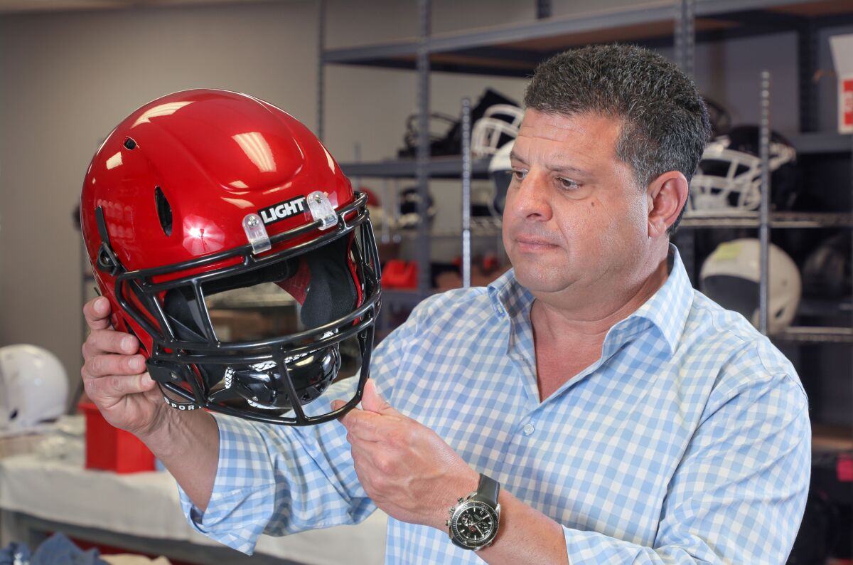 LIGHT Helmets CEO Nick Esayian holds a copy of one of the helmets that will be tried out by the San Diego State Aztecs football team this season.