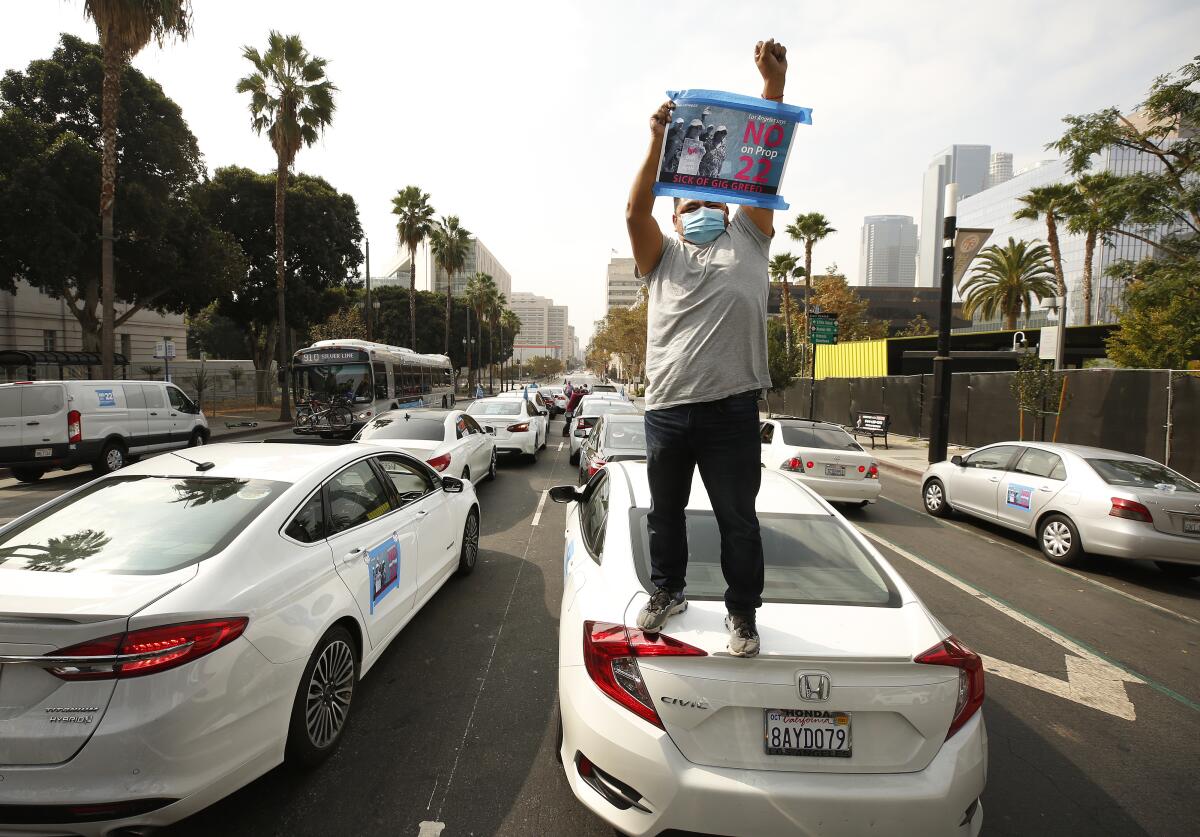 LOS ANGELES, CA - OCTOBER 08: Rideshare driver Jesus Ibarra stands on his car 