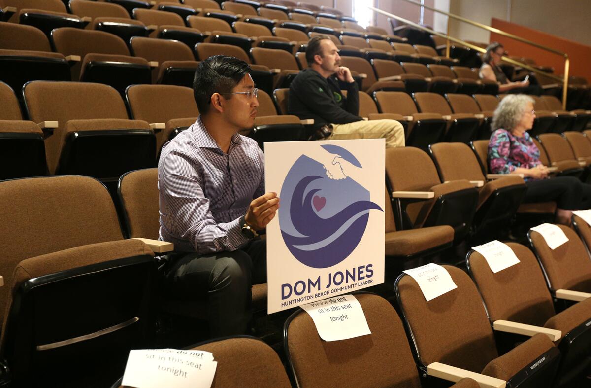 Richard Kuo holds a sign in support of Dom Jones during an interview for the vacant City Council seat.
