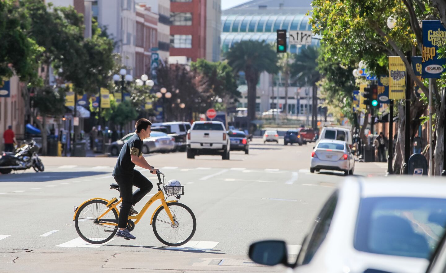 A person crosses 4th Avenue at G Street on an Ofo bike.