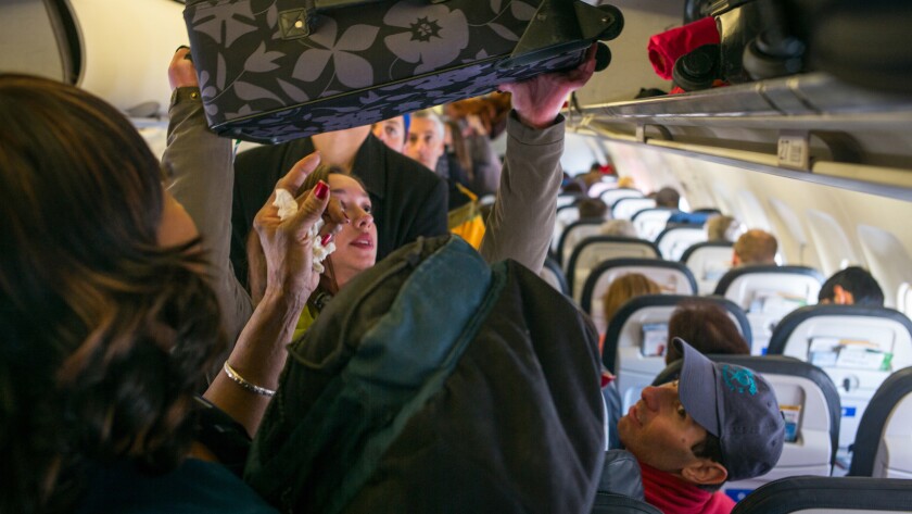 Passengers load their carry-on bags into overhead bins on a United Airlines flight March 6, 2015 at the Denver International Airport in Denver, Colorado.