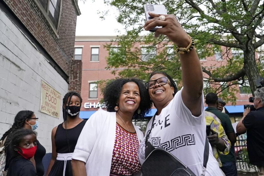 Boston's acting Mayor Kim Janey, left, takes a selfie with Mikey Miles as she meets people in Boston's Nubian Square for a Juneteenth commemoration, Friday, June 18, 2021, in Boston. (AP Photo/Elise Amendola)