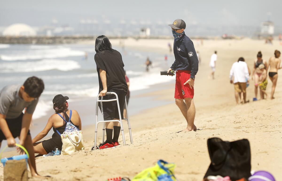 A Seal Beach lifeguard politely reminds beachgoers to keep in motion while enjoying a day at Seal Beach on Thursday.