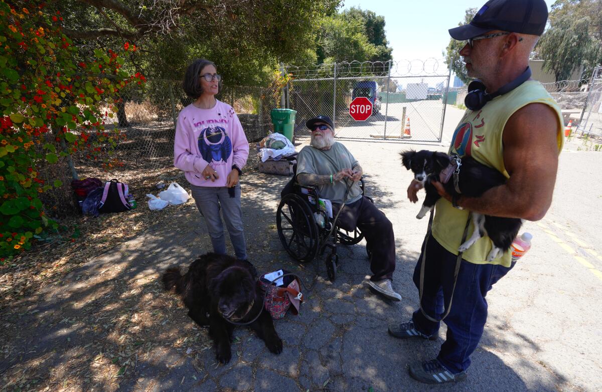 Jason Henning and his wife, Regina, along with their friend Brian Moore wait to enter San Diego’s safe-sleeping site