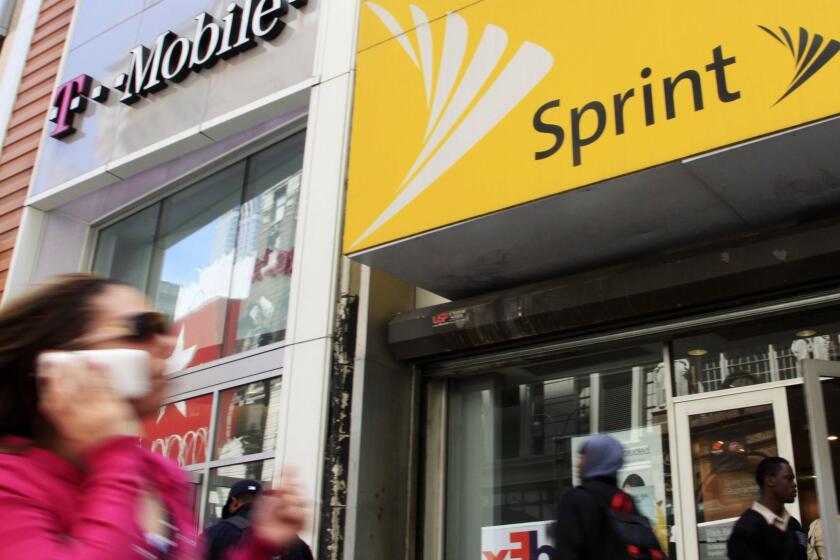 FILE- In this April 27, 2010 file photo, a woman using a cell phone walks past T-Mobile and Sprint stores in New York. T-Mobile and Sprint are trying again to combine in a deal that would reshape the U.S. wireless landscape, the companies announced Sunday, April 29, 2018 (AP Photo/Mark Lennihan, File)