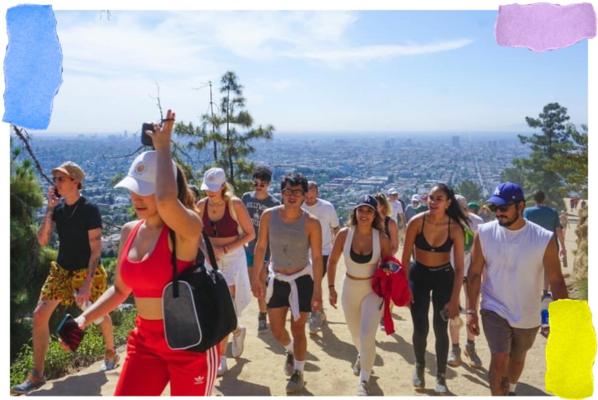 A group of people hike up a hill, with a city spread out behind them.