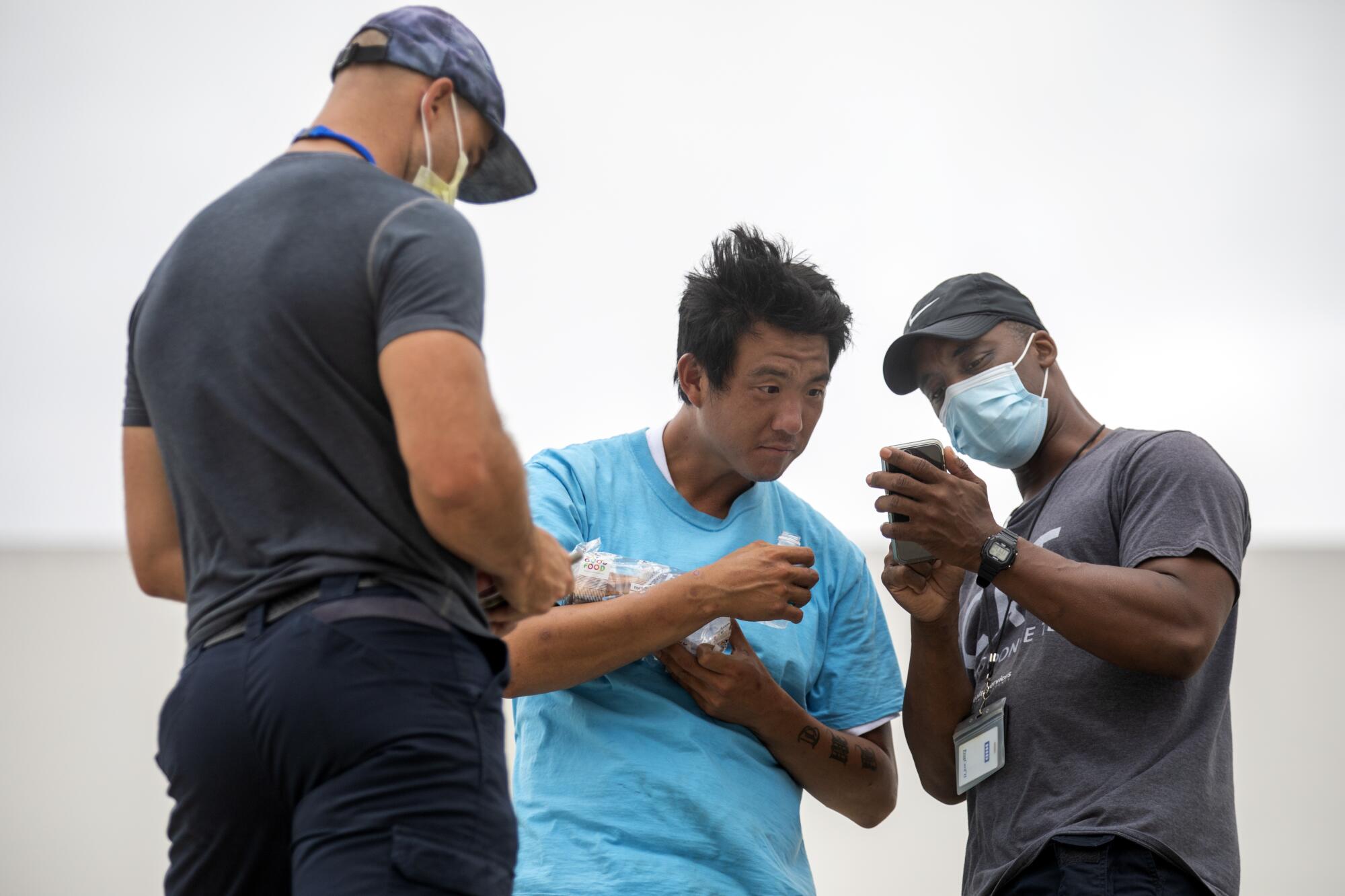 Members of the L.A. County Department of Health Services street medicine team examine a homeless man.