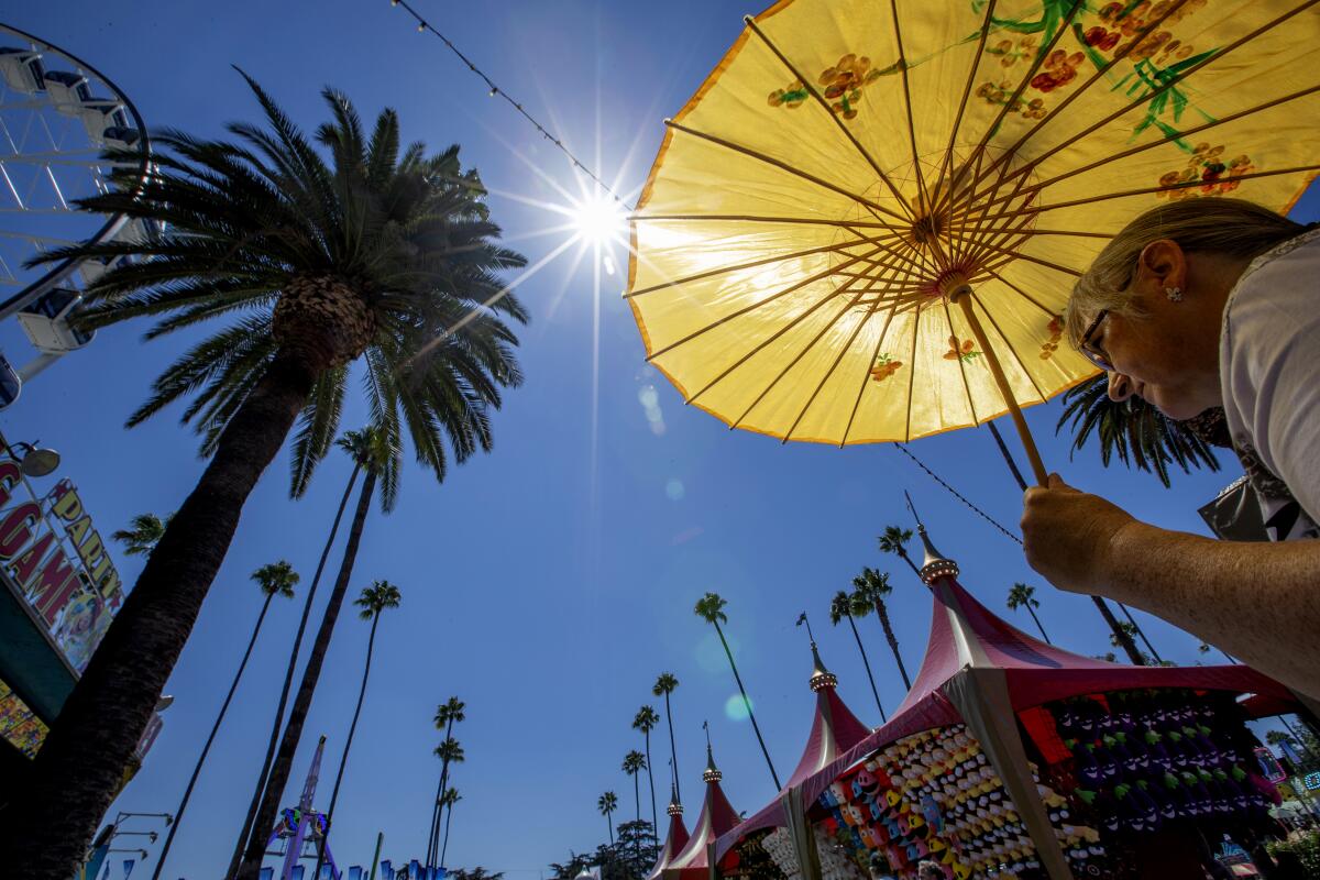 A pedestrian shields herself from the sun with a parasol. 