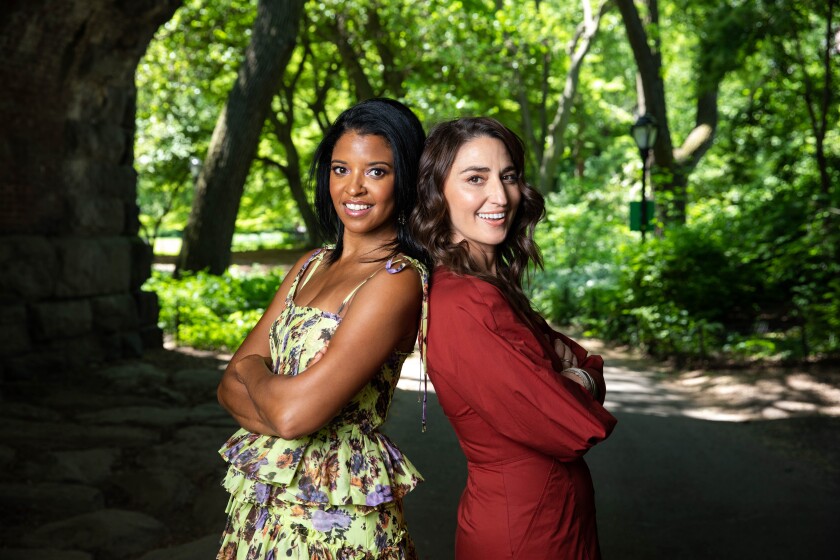 Renee Elise Goldsberry and Sara Bareilles pose back to back in Central Park. They star in the Peacock show "Girls5Eva."