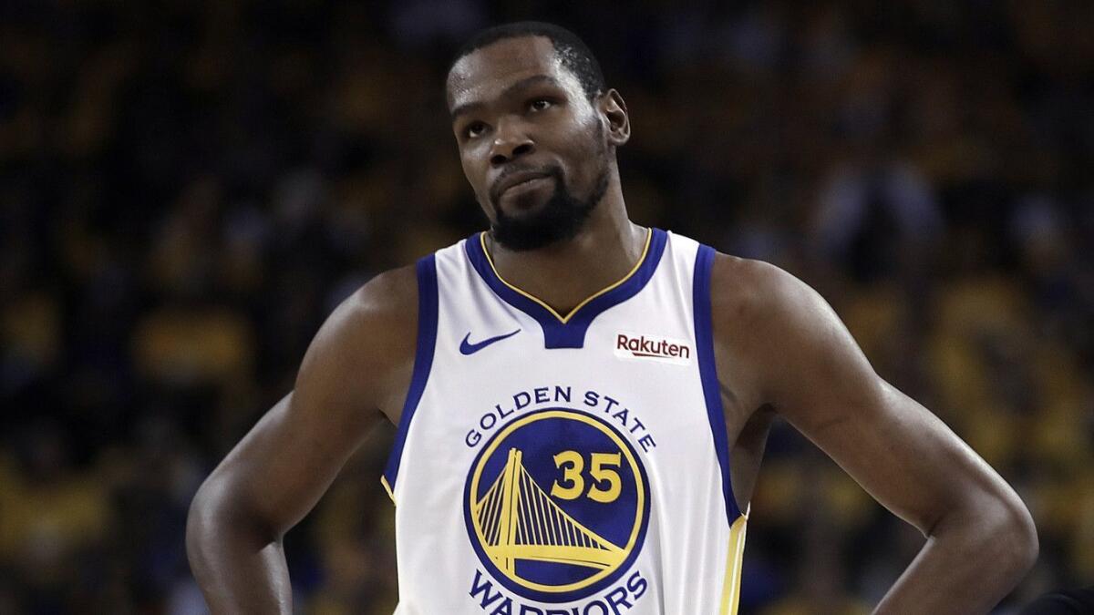 Golden State Warriors star Kevin Durant, left, looks on during Game 5 of the NBA Western Conference semifinals against the Houston Rockets on May 8.