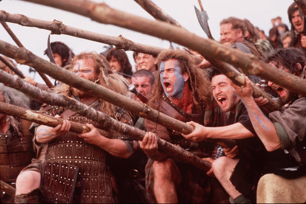 A group of warriors holding sticks stand in a line.