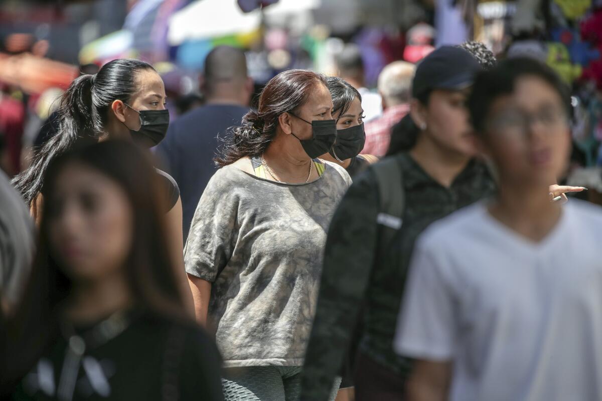 Shoppers with and without masks stroll in a congested market 