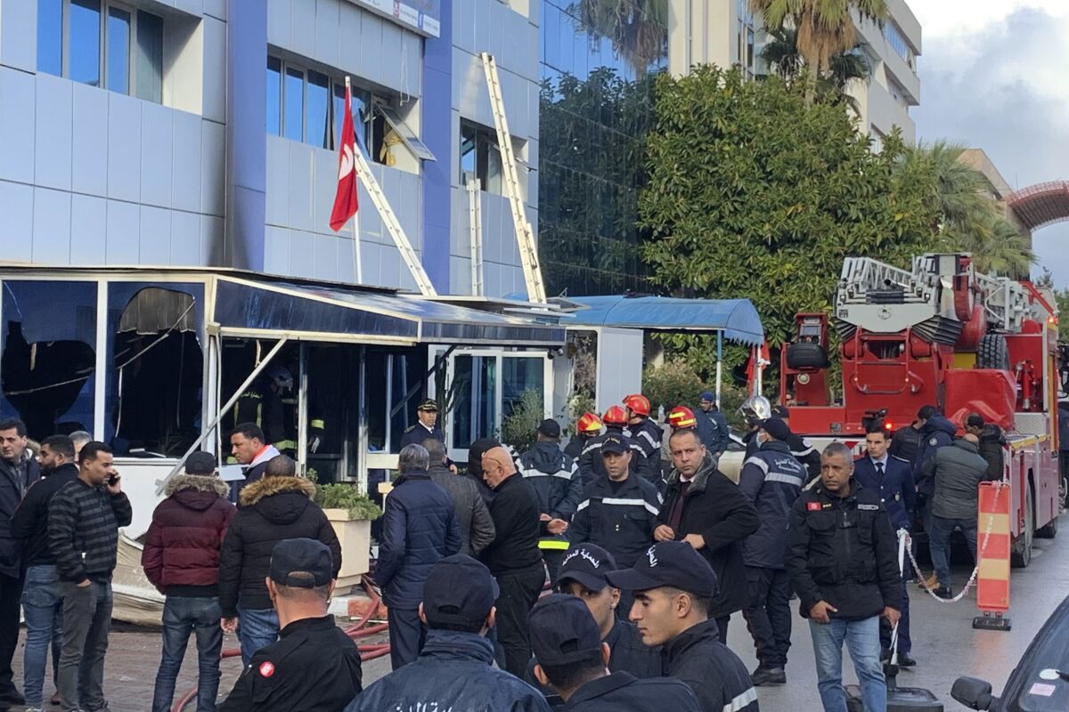 Firemen stand outside the Ennahda party headquarters after a fire broke out at Tunisia's Ennahda Tunisia's moderate Islamist party, Thursday, Dec.9, 2021 in Tunis. (AP Photo/Francesca Ebel)