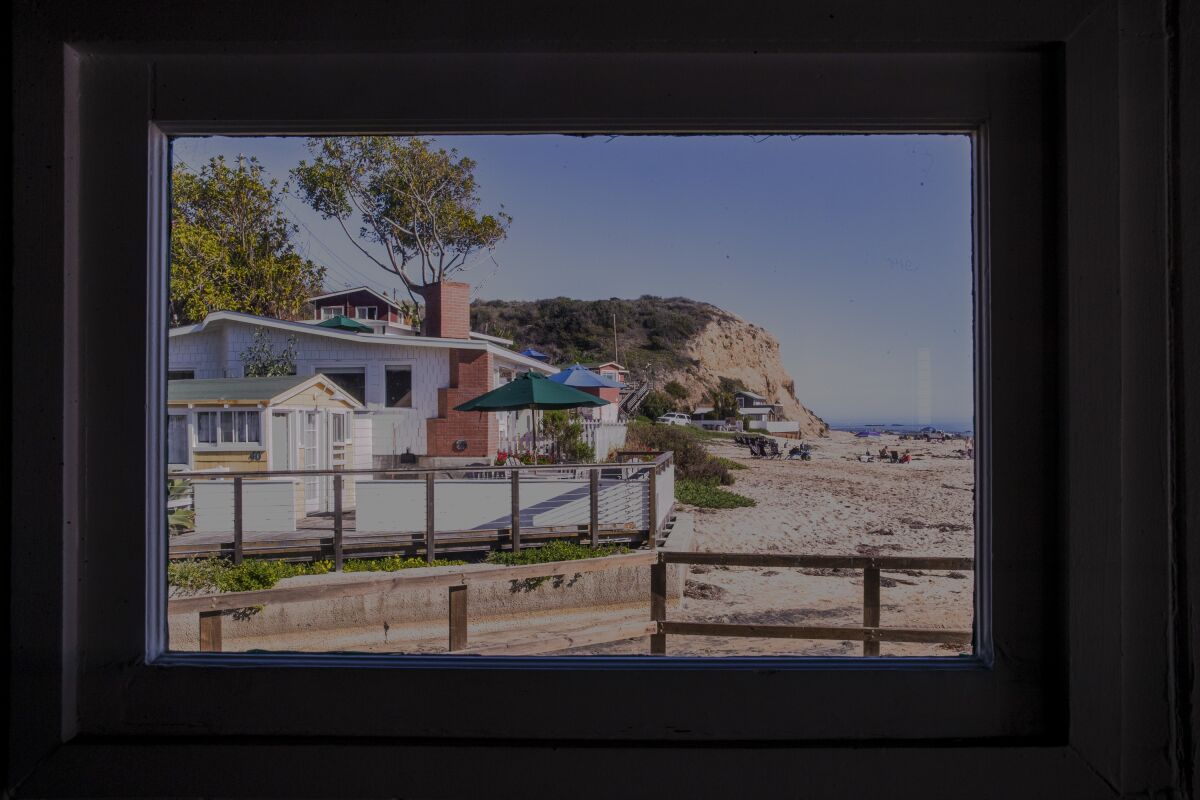 A view of cottages and the beach through a window.