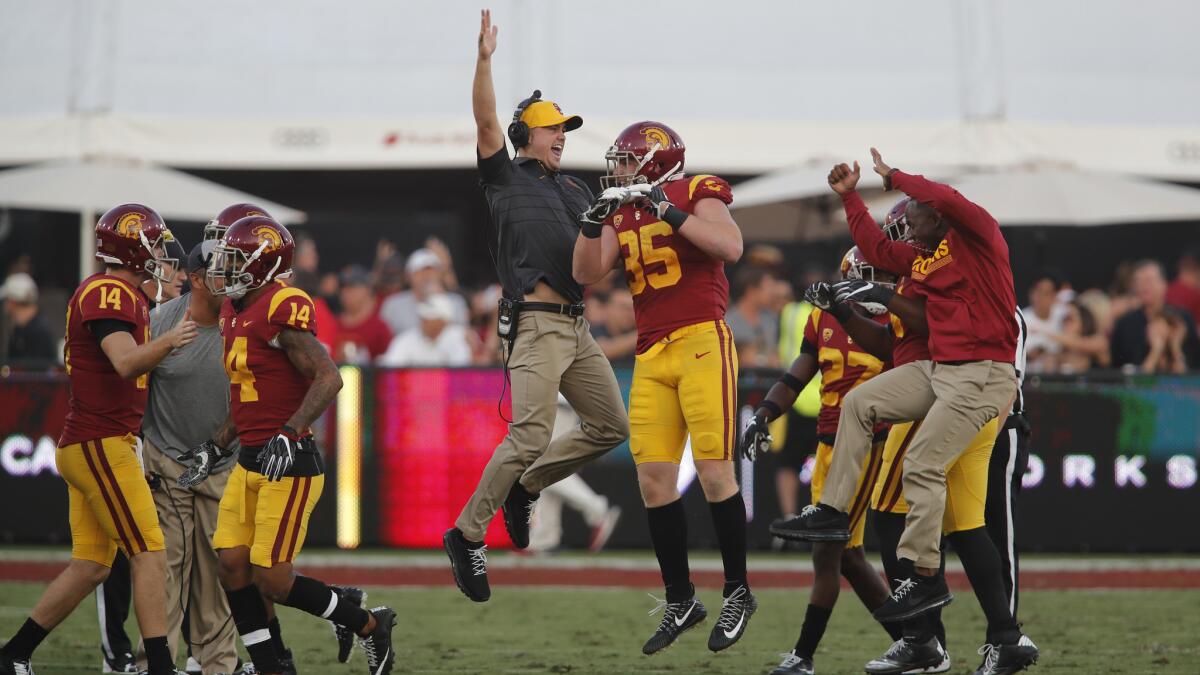 USC linebacker Cameron Smith (35) celebrates with his coaches after picking off a Troy Williams pass in the first quarter of a game at the Coliseum.