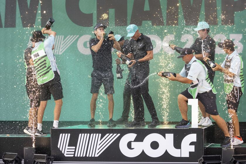 FILE - Team champions David Puig, Sebastián Muñoz, Mito Pereira, Captain Joaquín Niemann of Torque GC and their caddies celebrate on stage with the team trophy during LIV Golf DC at the Trump National Golf Club in Washington Sunday, May 28, 2023, in Sterling, Virginia. The most disruptive year in golf ended Tuesday, June 6, 2023, when the PGA Tour and European tour agreed to a merger with Saudi Arabia's golf interests, creating a commercial operation designed to unify professional golf around the world.(Photo by Chris Trotman/LIV Golf via AP, File)