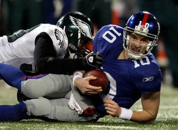 Eli Manning of the New York Giants gets sacked late in the game by Will Witherspoon of the Philadelphia Eagles at Giants Stadium on in East Rutherford, New Jersey.
