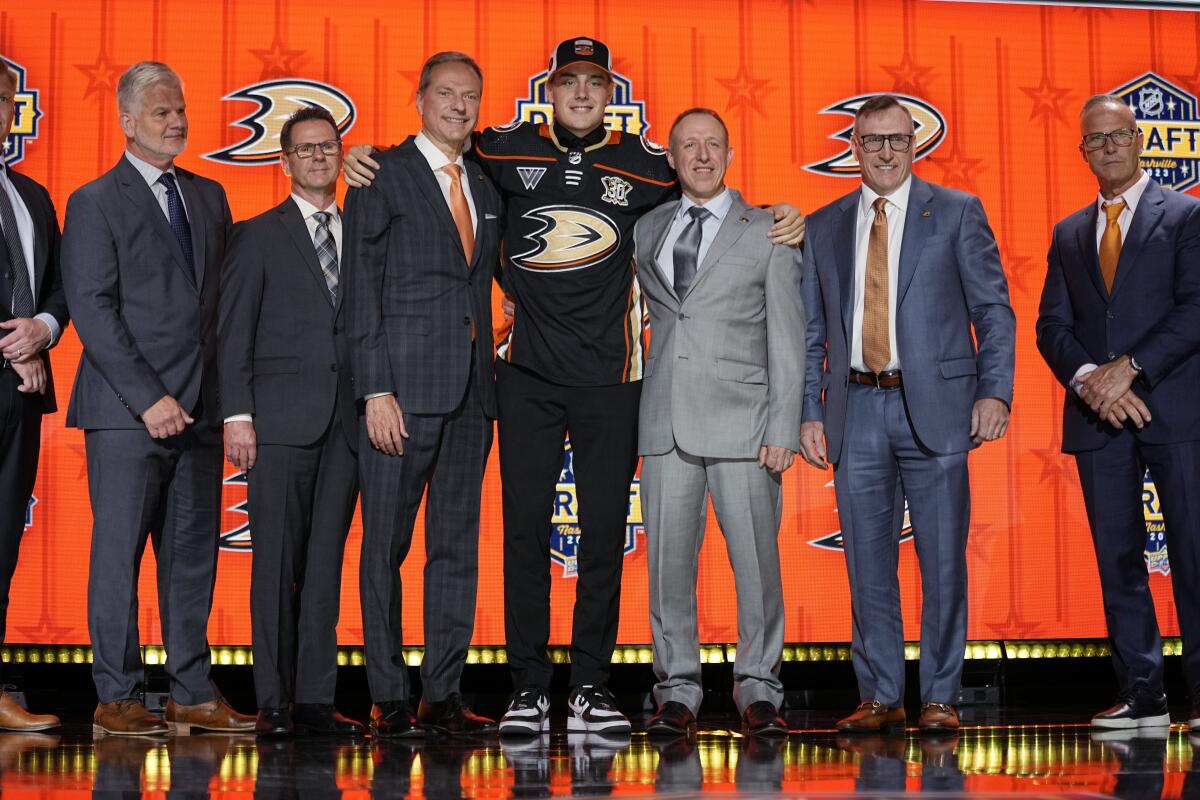 Leo Carlsson poses with Ducks officials after being picked by the team during the first round of the NHL draft.