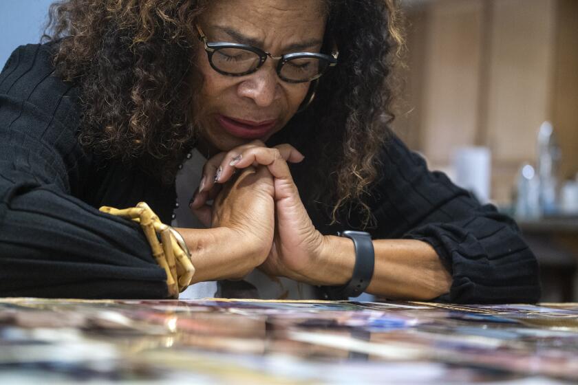 MORENO VALLEY, CA - OCTOBER 11: Sheryll Bell looks at photographs of her son during an interview with the Los Angeles Times on Monday, Oct. 11, 2021 in Moreno Valley, CA. Sheryll Bell is the mother of Julian Alexander, a 21-year-old man who was killed by Anaheim police in 2008. She has kept his memory alive ever since through a scholarship, but his name is only finally being talked about in the same breath as George Floyd, Philando Castile, and other Black men and women killed by police. (Francine Orr / Los Angeles Times)