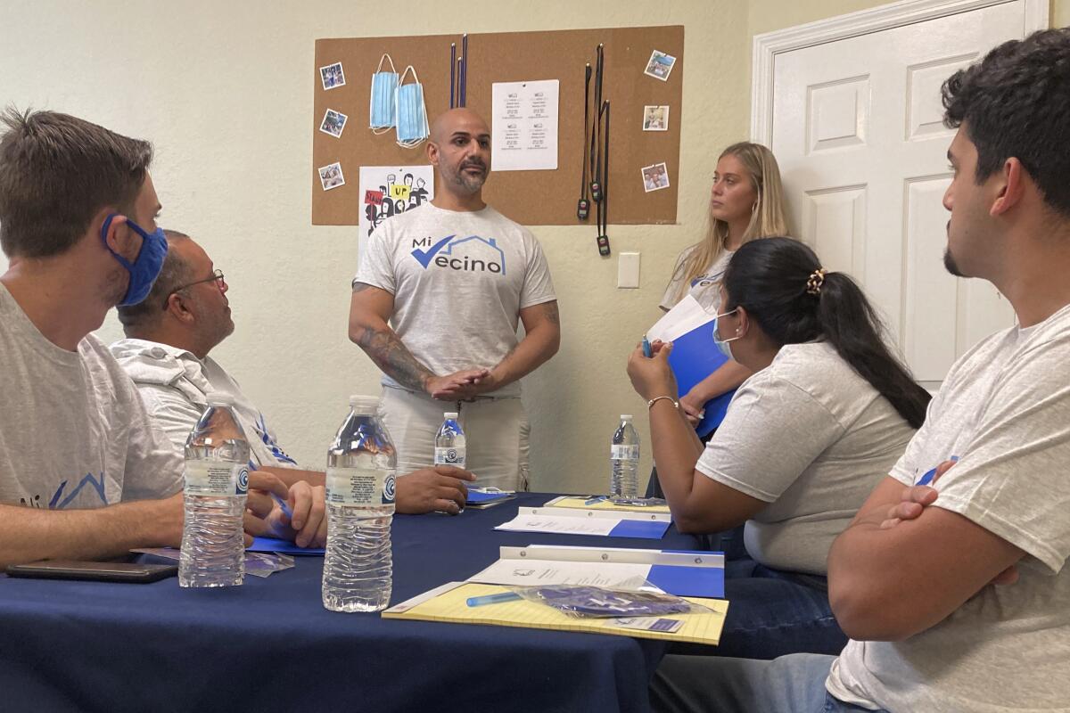 Alex Berrios, left, and Devon Murphy-Anderson, right, co-founders of the nonprofit Mi Vecino, coach newly hired staff members on how best to approach people and convince them to register to vote on June 24, 2021, in Kissimmee, Fla. Their group, and other advocacy organizations affiliated with Democrats, are trying to engage Latino voters earlier and build lasting relationships after Republicans gained ground with voters in some Latino communities during last year's presidential and congressional races. (AP Photo/Will Weissert)
