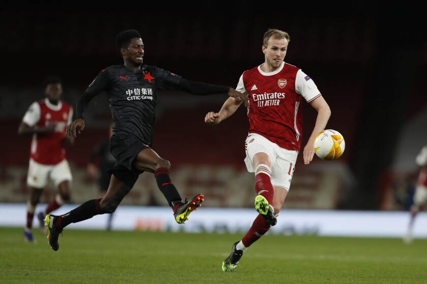 Arsenal's Rob Holding, right, passes the ball as Slavia Prague's Peter Olayinka tries to sop him during the Europa League quarterfinal soccer match between Arsenal and Slavia Prague at Emirates stadium in London, Thursday, April 8, 2021. (AP Photo/Alastair Grant)