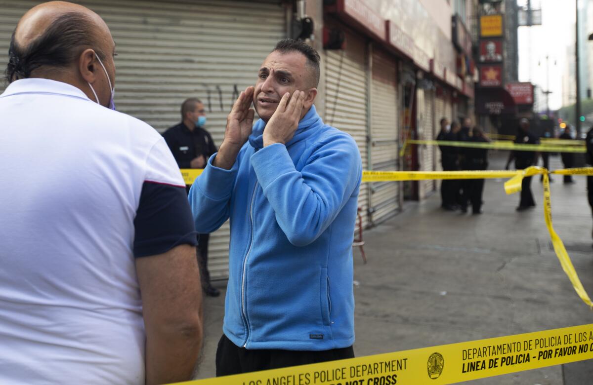 A man reacts with distress outside a crime scene in downtown L.A.
