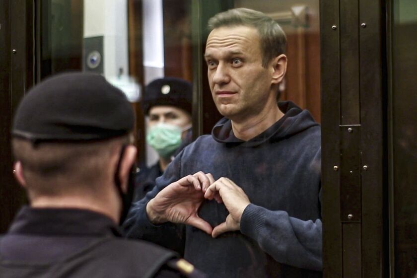 FILE In this file photo made from video provided by the Moscow City Court on Feb. 3, 2021, Russian opposition leader Alexei Navalny makes a heart gesture standing in a cage during a hearing to a motion from the Russian prison service to convert the suspended sentence of Navalny from the 2014 criminal conviction into a real prison term in the Moscow City Court in Moscow, Russia. Navalny, President Vladimir Putin's fiercest foe, has become Russia's most famous political prisoner. He is serving a nine-year term due to end in 2030 on charges widely seen as trumped up, and is facing another trial on new charges that could keep him locked up for another two decades. (Moscow City Court via AP, File)