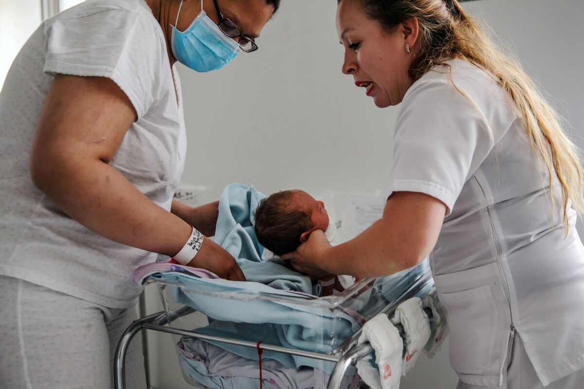 Belys Torrealba Tovar, 24, left, reaches for her newborn, Angel, at the Hospital Materno Infantil in Bogota, Colombia. She hopes to return to Venezuela so he can have citizenship.