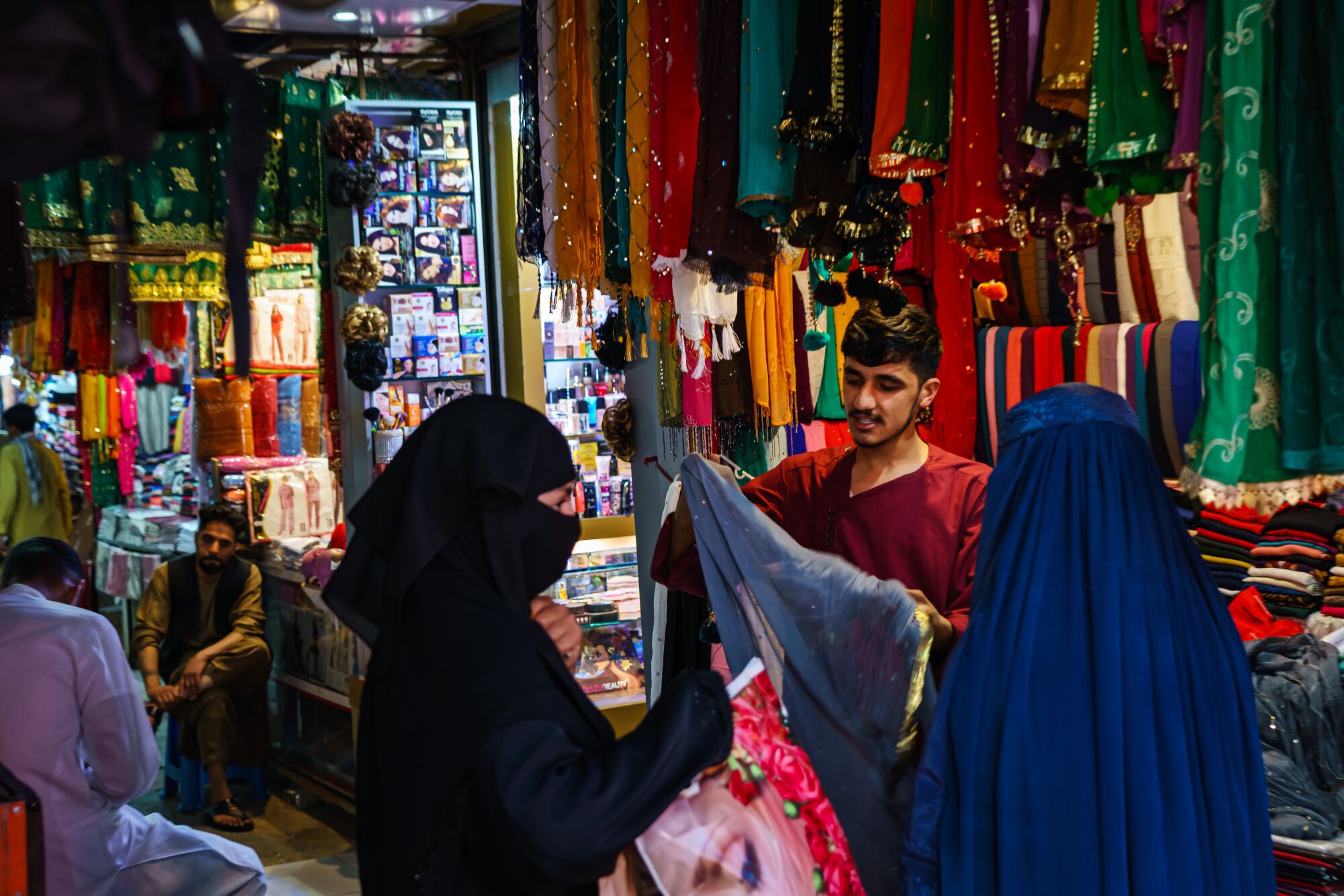A shopkeeper shows his wares to the women shopping in the Lycee Maryam Bazaar in Kabul, Afghanistan.