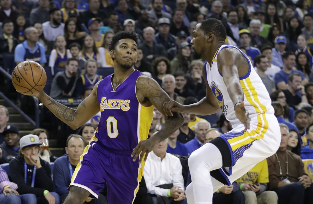 Lakers' Nick Young, left, looks to pass as Golden State Warriors' Kevin Durant defends during the first half of a game on Nov. 23.