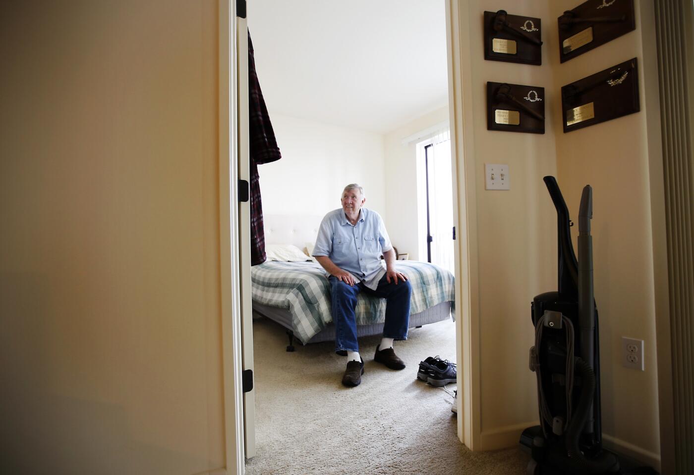 Resident Terry Conner, 73, sits on his bed, putting on his shoes in his apartment at The Woods at Playa.