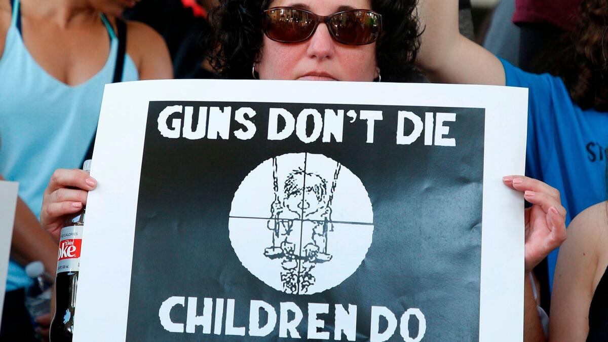 Protesters hold signs at a rally at the Broward County Federal Courthouse in Fort Lauderdale, Fla. on Feb. 17, Seventeen perished in the hail of bullets at Marjory Stoneman Douglas High School in Parkland, Fla. A reader writes to say guns are too popular in La Cañada.