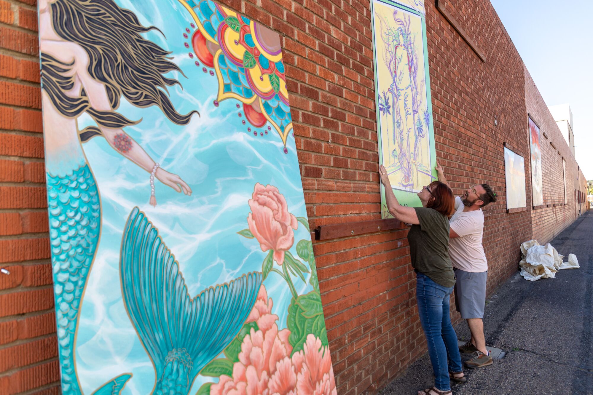 Escondido Art Association committee members Heather Moe and Tristan Pittard install artist mural panels