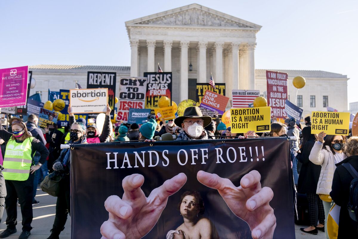 FILE - Stephen Parlato of Boulder, Colo., holds a sign that reads "Hands Off Roe!!!" as abortion rights advocates and anti-abortion protesters demonstrate in front of the U.S. Supreme Court, Dec. 1, 2021, in Washington, as the court hears arguments in a case from Mississippi, where a 2018 law would ban abortions after 15 weeks of pregnancy, well before viability. Abortion funds, entities that raise money to aid women get abortions, say they would need more donations this year if the U.S. Supreme Court makes seismic changes to the nationwide right to abortion. (AP Photo/Andrew Harnik, File)