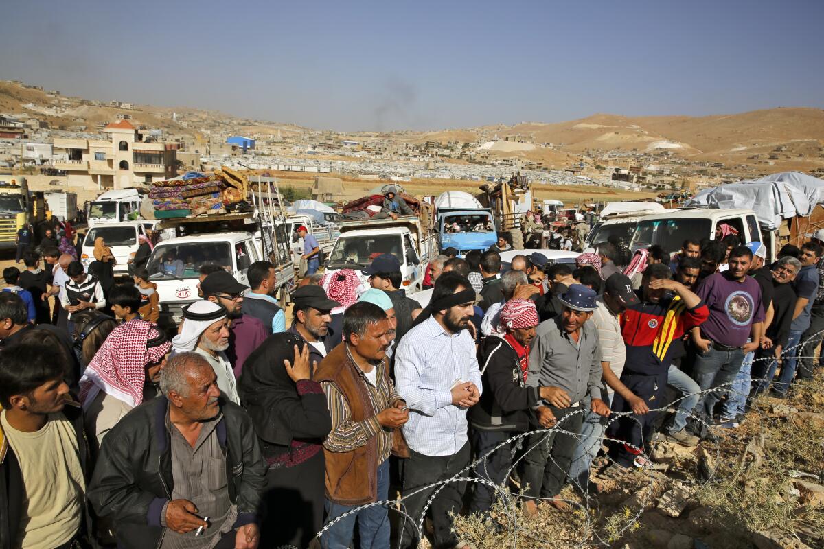 FILE - In this June 28, 2018 file photo, Syrian refugees gather in and near their vehicles getting ready to cross into Syria from the eastern Lebanese border town of Arsal, Lebanon. A number of Syrian refugees who returned home have been subjected to detention, disappearance and torture at the hands of Syrian security forces, proving that it still isn't safe to return to any part of the country, Amnesty International said in a new report released Tuesday, Sept. 7, 2021. It documents what it said were violations committed by Syrian intelligence officers against some returnees, including 13 children between mid-2017 and spring 2021. (AP Photo/Bilal Hussein, File)