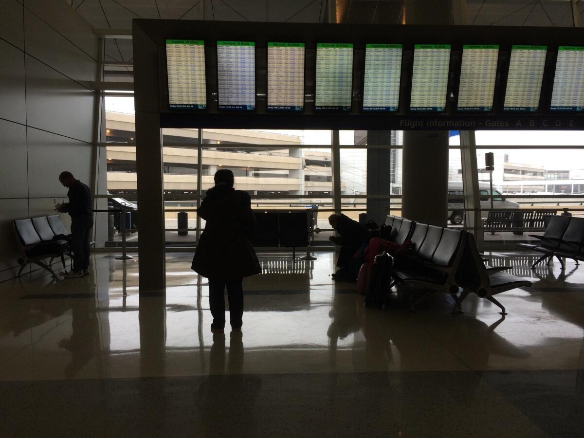 In a precursor of weekend delays, a traveler on Monday reads a flight tracking board showing numerous cancellations at Dallas-Fort Worth International Airport.