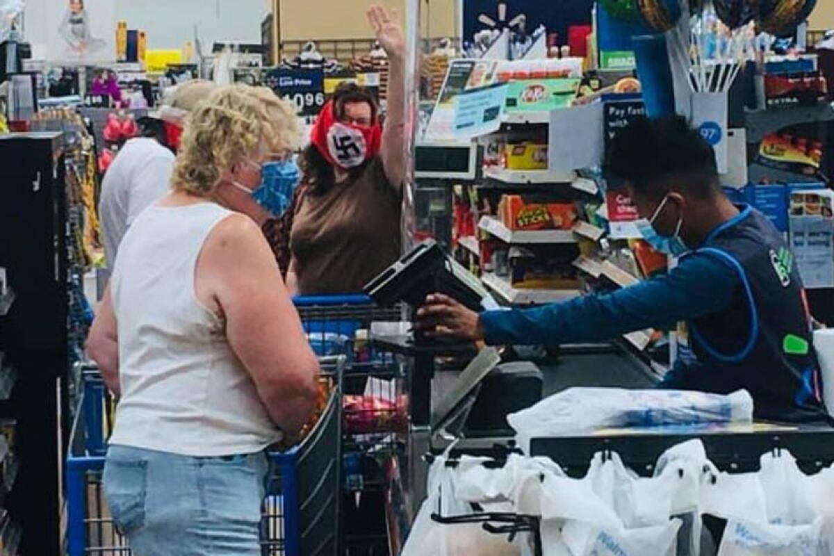 A woman wearing a swastika mask gestures to other Walmart shoppers in Marshall, Minn., on Saturday.
