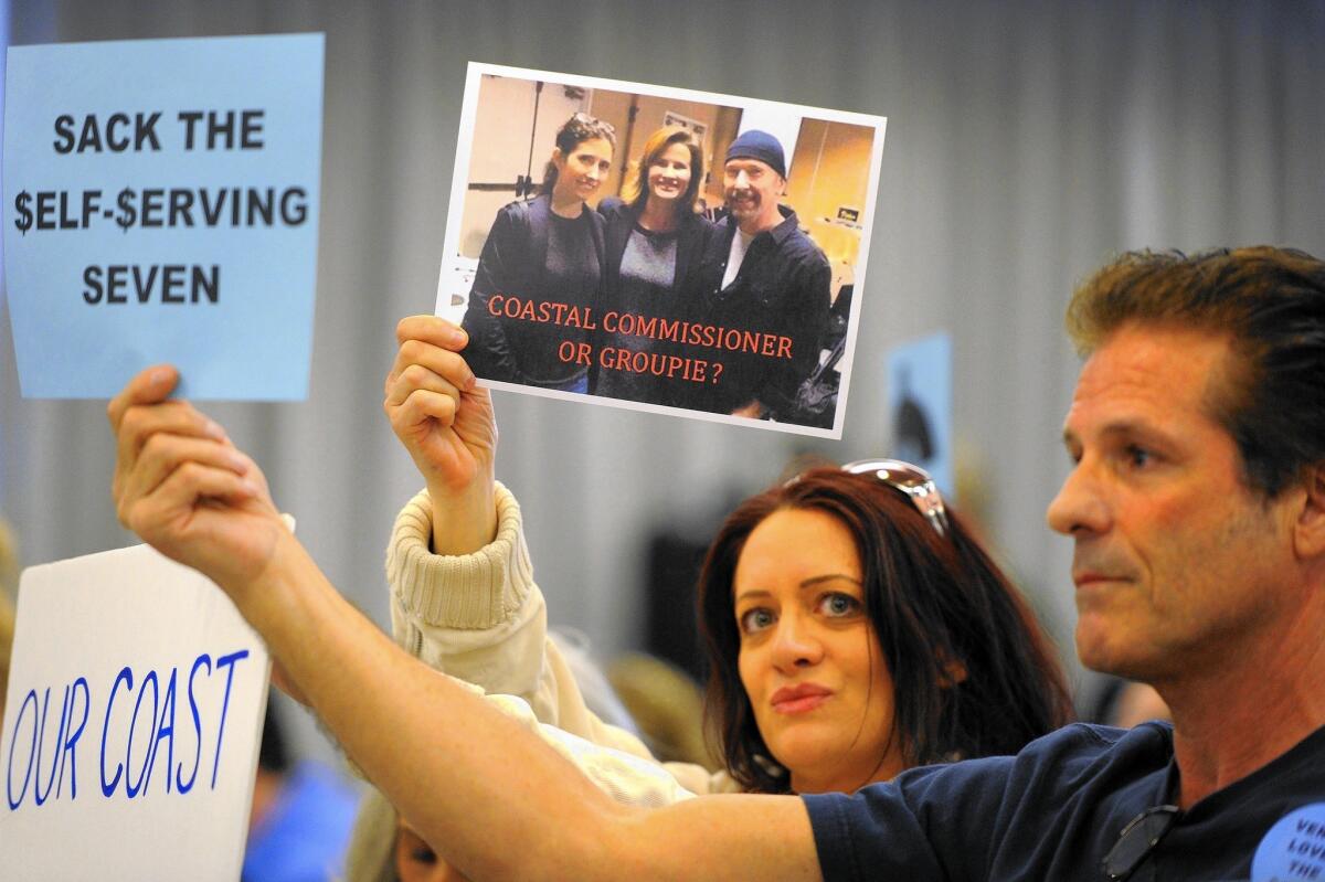 Ilana Marosi holds a photo of Commissioner Wendy Mitchell with U2 guitarist David Evans.