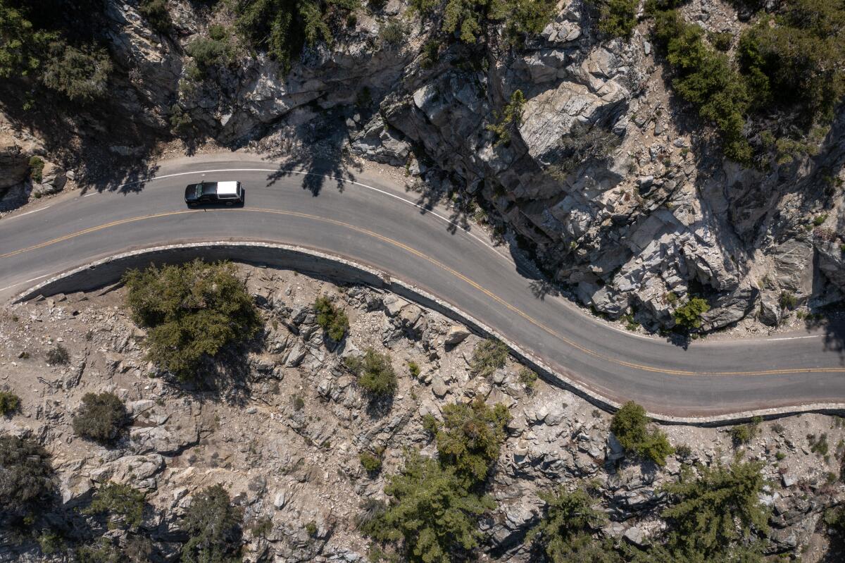 An aerial view of a road snaking through a mountain wilderness. 