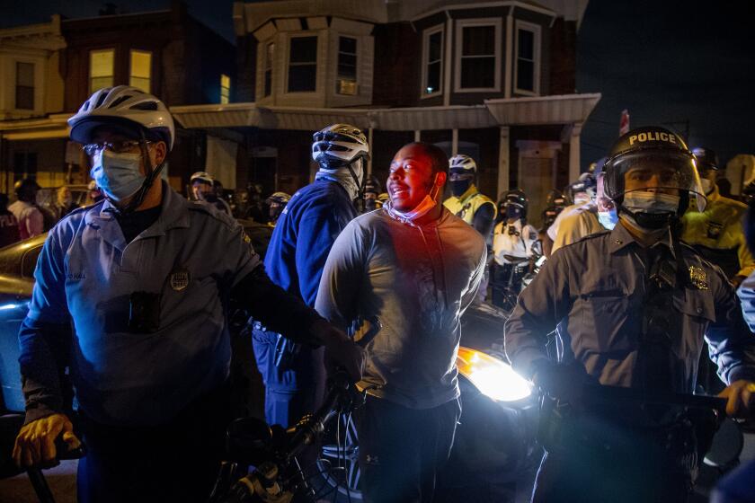 A person is handcuffed and detained by police at 55th and Pine Street, Wednesday, Oct. 28, 2020, in Philadelphia, after the citywide curfew had passed, two days after Walter Wallace Jr. was killed by police officers. (Tom Gralish/The Philadelphia Inquirer via AP)