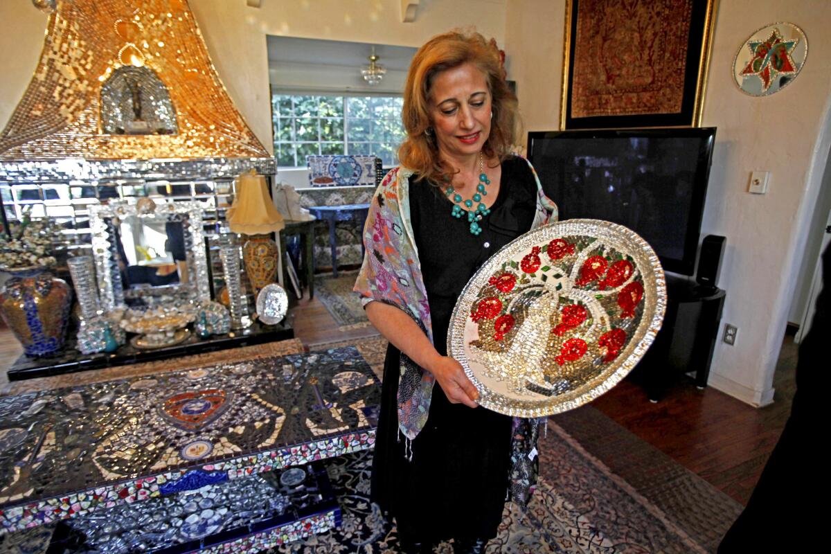 Louise Farnam holds a platter she made. She also decorates mirrors, tables and other interior furnishings, which she sells via her small business.