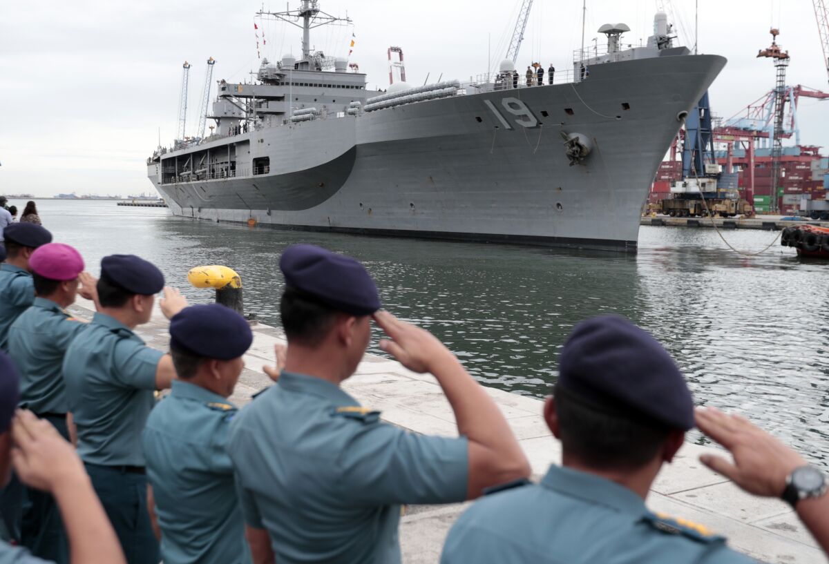 Indonesian Navy officers salute as U.S. Navy ship Blue Ridge prepares to dock at Tanjung Priok Port