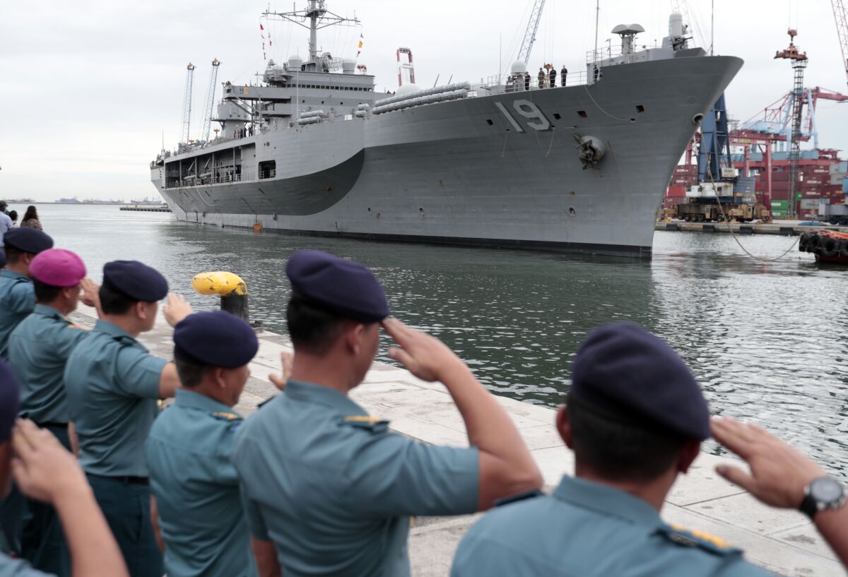 Indonesian Navy officers salute as U.S. Navy ship Blue Ridge prepares to dock at Tanjung Priok Port