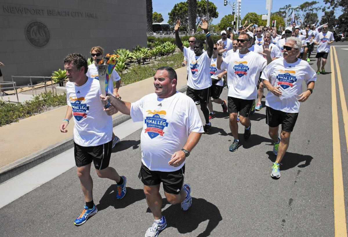 Dale Smit, left, a Special Olympics athlete from New Zealand, and Mike Still, communications officer with the South Carolina Department of Public Safety, carry the Flame of Hope as they arrive at the Newport Beach Civic Center on Monday during the Law Enforcement Torch Run for the Special Olympics World Games, which begin Saturday in Los Angeles.