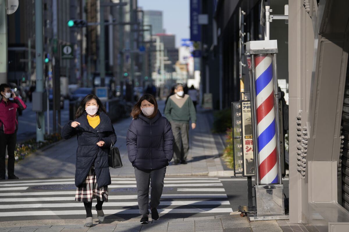 Women wearing face masks walk along the sidewalk in Tokyo, Wednesday, Feb. 9, 2022. (AP Photo/Hiro Komae)