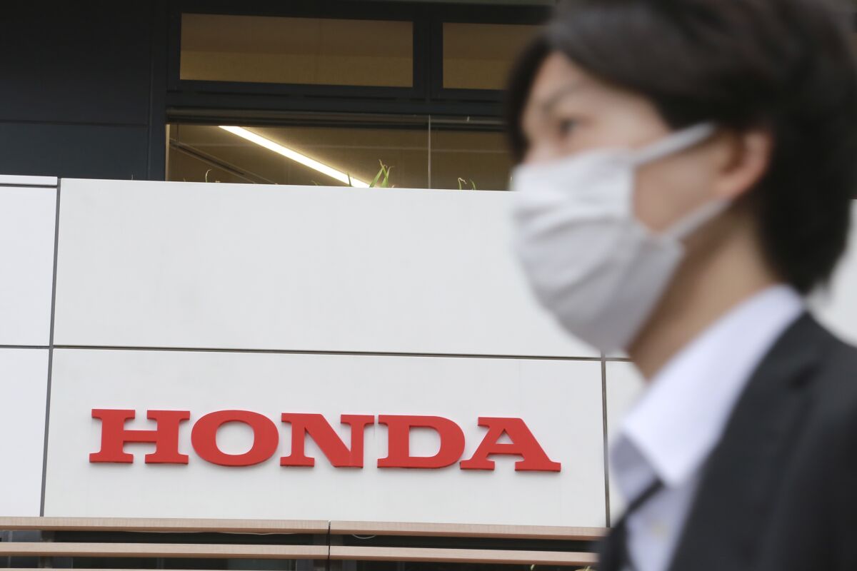 A man walks past the logo of Honda Motor Co. in Tokyo on Oct. 19, 2021. Japanese automaker Honda lowered its profit and vehicle sales forecasts for the fiscal year Friday, pointing to a supply crunch in chips and rising material costs. (AP Photo/Koji Sasahara)