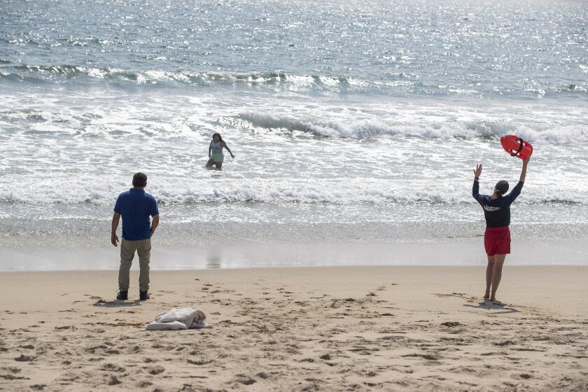 A lifeguard calls out to a girl to get out of the water at Dockweiler State Beach in Playa del Rey.