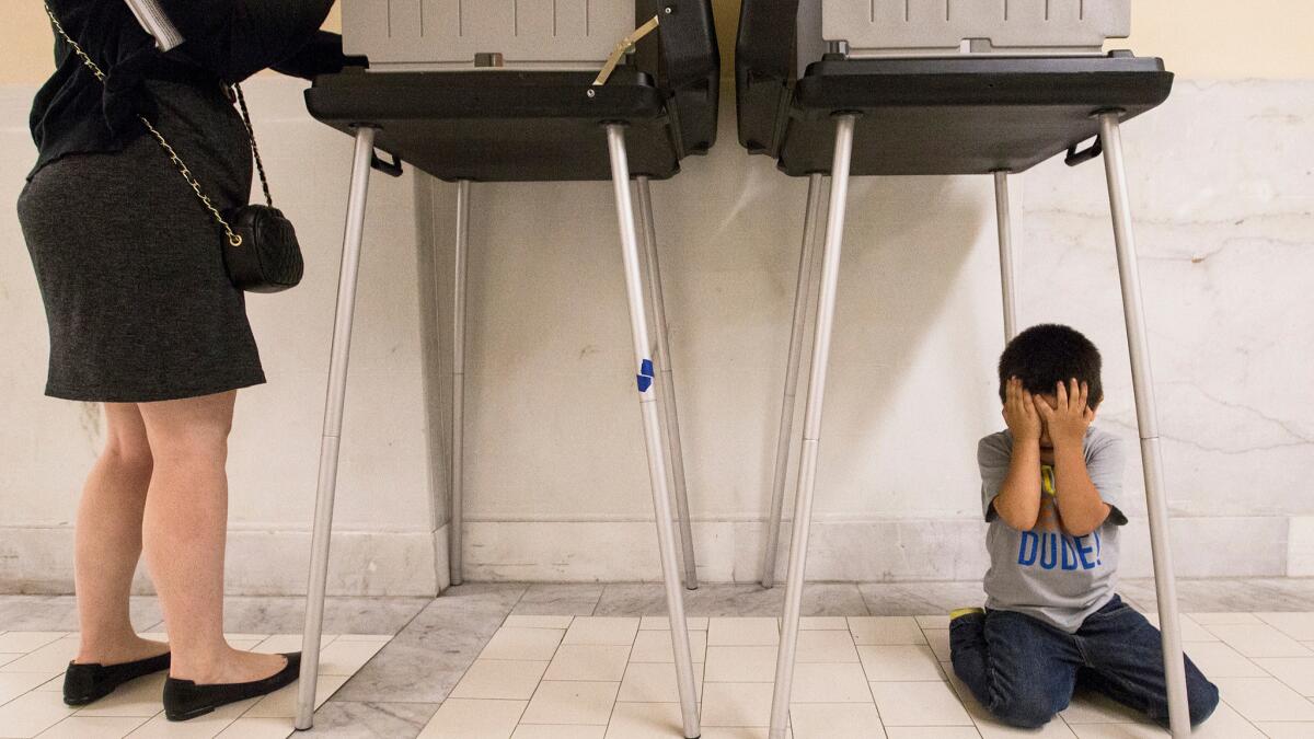 Johnny Lucero, 3, plays underneath a polling box while his mother, Nicanora Contreras, casts her vote Tuesday at San Francisco City Hall.