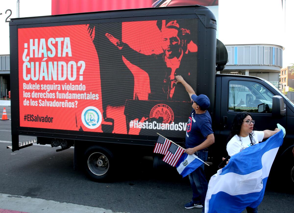 A truck with a digital sign passes by protesters