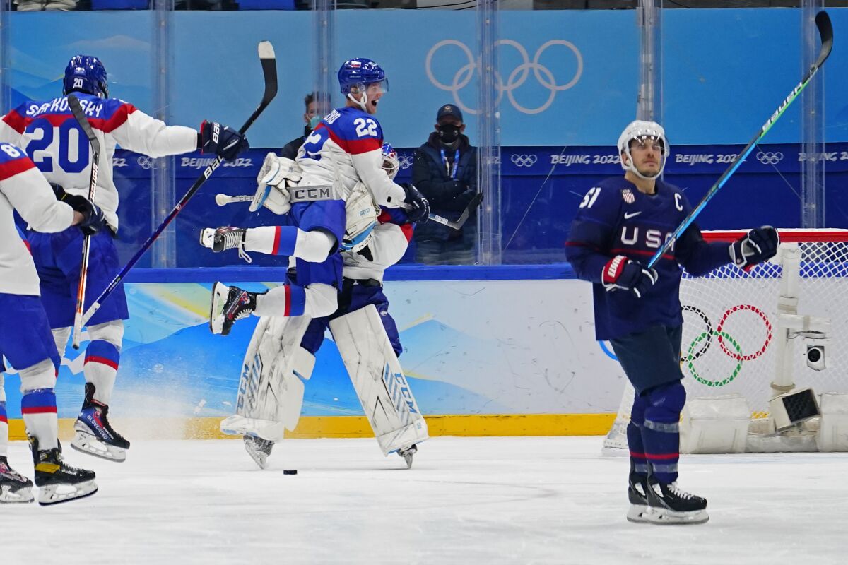 Slovakia's Samuel Knazko (22) jumps onto goalkeeper Patrik Rybar after Rybar blocked the final shoot-out attempt by United States' Andy Miele, right, during a men's quarterfinal hockey game at the 2022 Winter Olympics, Wednesday, Feb. 16, 2022, in Beijing. Slovakia won 3-2. (AP Photo/Matt Slocum)